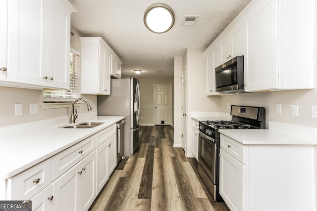 1421 Oak Knoll Dr NE, Conyers, GA 30012 - kitchen with stainless steel appliances, white cabinetry, wood finished floors, light countertops, and a textured ceiling