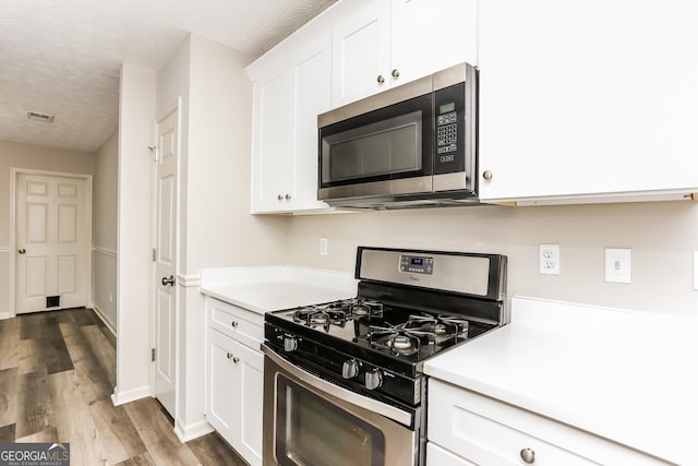 1421 Oak Knoll Dr NE, Conyers, GA 30012 - kitchen with appliances with stainless steel finishes, wood finished floors, white cabinetry, light countertops, and a textured ceiling