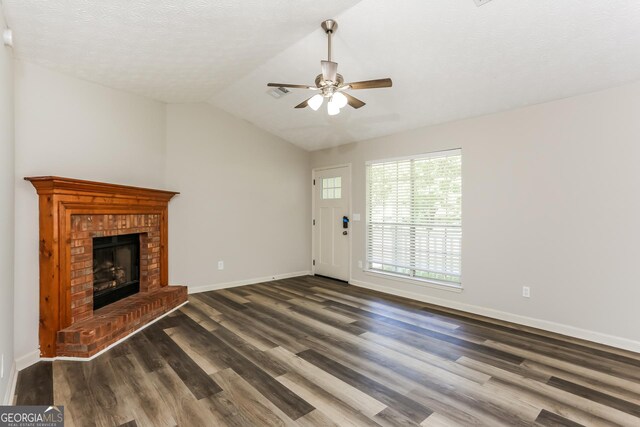 1421 Oak Knoll Dr NE, Conyers, GA 30012 - unfurnished living room featuring dark wood-style flooring, a ceiling fan, a brick fireplace, a textured ceiling, and vaulted ceiling