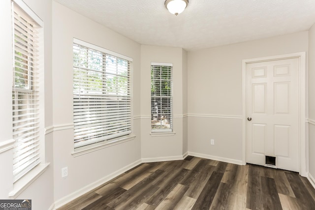 1421 Oak Knoll Dr NE, Conyers, GA 30012 - empty room featuring dark wood-type flooring, healthy amount of natural light, and a textured ceiling