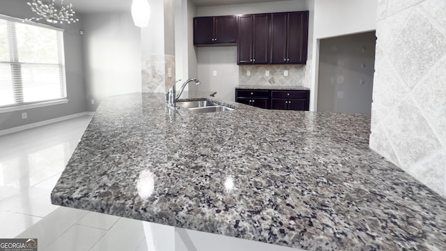 3368 Alhambra Cir, Hampton, GA 30228 - kitchen with dark stone countertops, tasteful backsplash, dark brown cabinetry, light tile patterned floors, and a peninsula