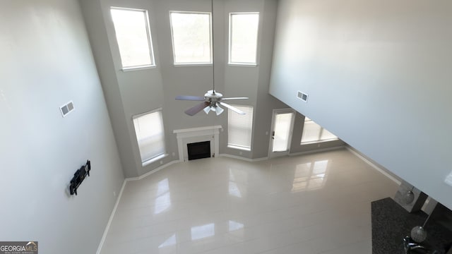3368 Alhambra Cir, Hampton, GA 30228 - unfurnished living room with ceiling fan, a fireplace, a towering ceiling, and light tile patterned floors