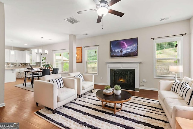 255 Hamilton Dr, Newnan, GA 30263 - living room with wood finished floors, a ceiling fan, a lit fireplace, a chandelier, and recessed lighting