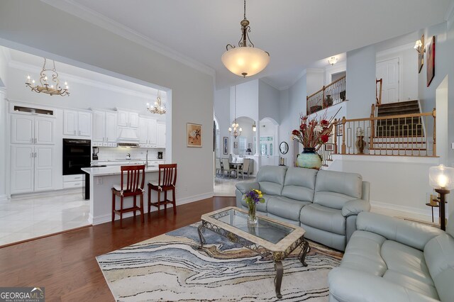 1000 Collingtree Ct, Mcdonough, GA 30253 - living area featuring a chandelier, arched walkways, crown molding, stairway, and light wood-style floors