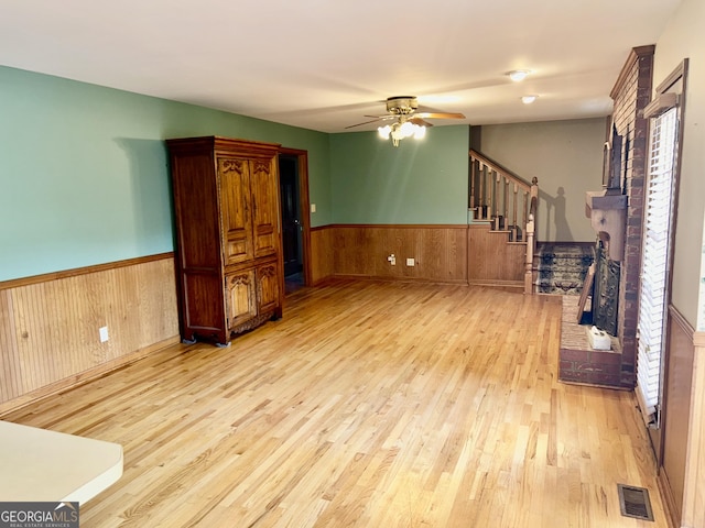 4494 Anderson Hwy, Hartwell, GA 30643 - unfurnished living room with wood finished floors, ceiling fan, wainscoting, wooden walls, and stairway