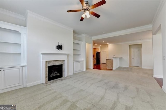 3411 Lindenridge Dr, Buford, GA 30519 - unfurnished living room with ornamental molding, built in shelves, light carpet, ceiling fan, and a fireplace with flush hearth