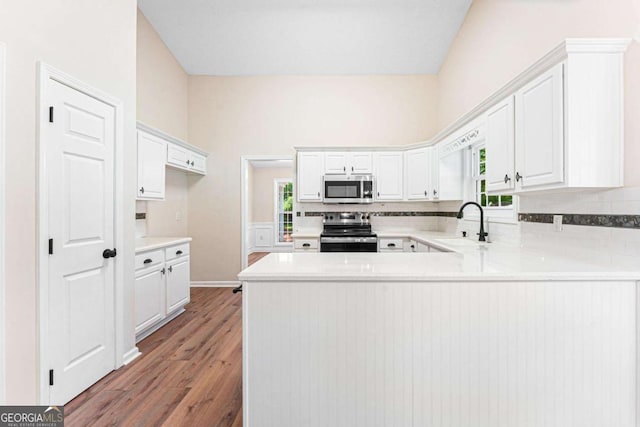 4210 Platinum Ct, Hoschton, GA 30548 - kitchen with appliances with stainless steel finishes, a peninsula, light wood-type flooring, white cabinetry, and light countertops