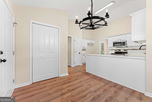 4210 Platinum Ct, Hoschton, GA 30548 - kitchen with appliances with stainless steel finishes, a chandelier, light wood finished floors, white cabinetry, and light countertops