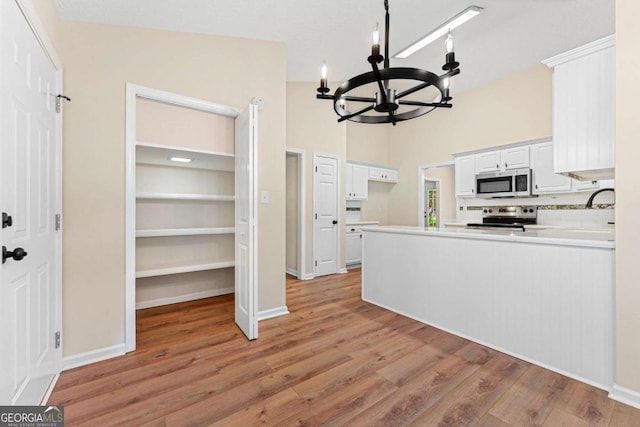 4210 Platinum Ct, Hoschton, GA 30548 - kitchen featuring appliances with stainless steel finishes, a chandelier, light wood-type flooring, white cabinetry, and light countertops