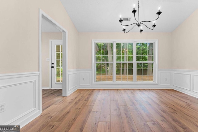 4210 Platinum Ct, Hoschton, GA 30548 - unfurnished dining area featuring a chandelier, wainscoting, wood finished floors, and a decorative wall