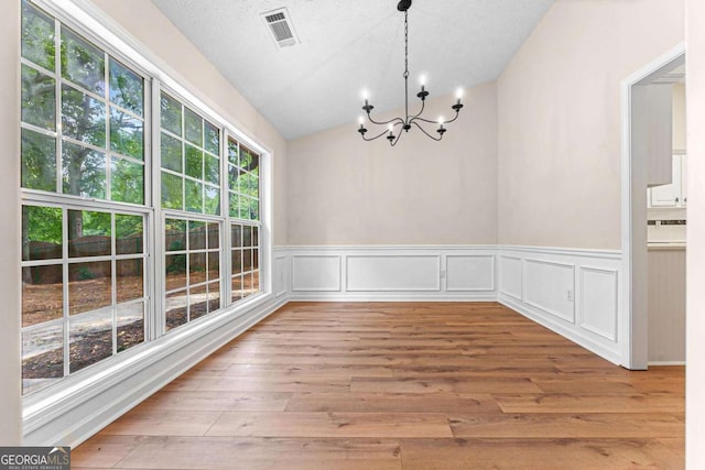 4210 Platinum Ct, Hoschton, GA 30548 - unfurnished dining area with a chandelier, vaulted ceiling, wainscoting, and wood finished floors