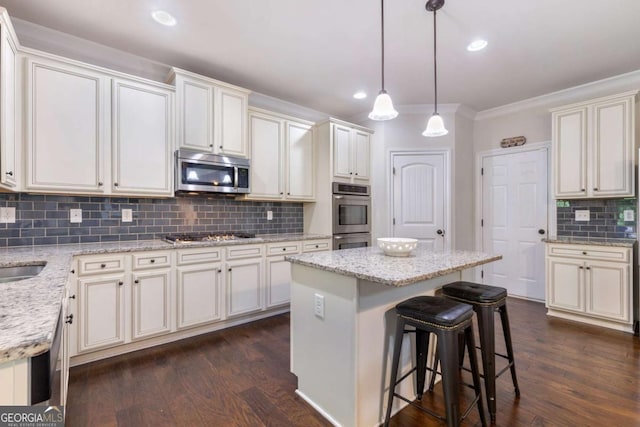 2307 Loughridge Dr, Buford, GA 30519 - kitchen featuring appliances with stainless steel finishes, tasteful backsplash, dark wood-type flooring, ornamental molding, and a center island