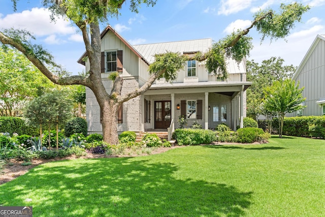 31 Frederica Oaks Ln, Saint Simons, GA 31522 - view of front facade featuring a front lawn, a standing seam roof, board and batten siding, a metal roof, and french doors