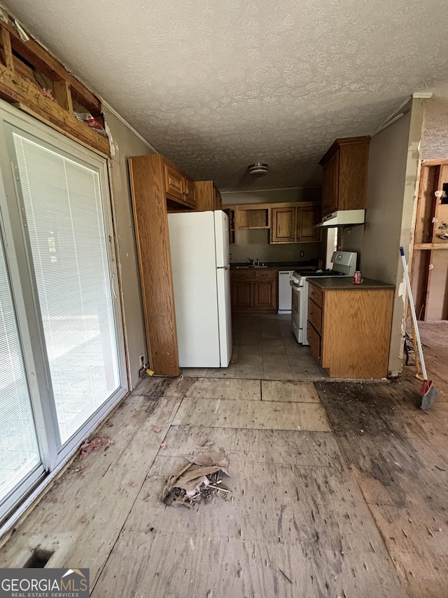 307 Hickman Rd, Forsyth, GA 31029 - kitchen with white appliances, dark countertops, under cabinet range hood, brown cabinets, and a textured ceiling