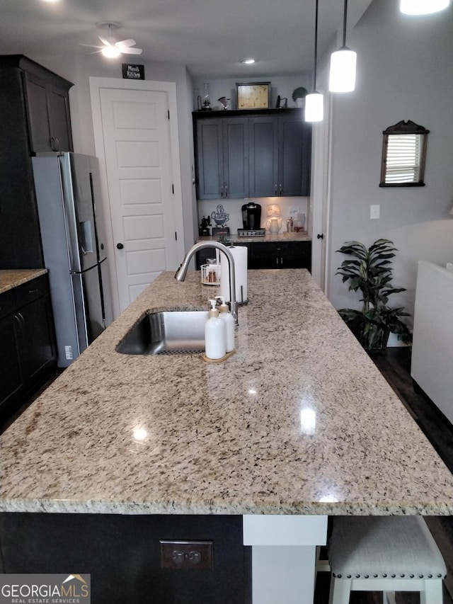 211 Barnyard Way, Perry, GA 31069 - kitchen featuring stainless steel fridge, light stone countertops, a center island with sink, a breakfast bar area, and pendant lighting