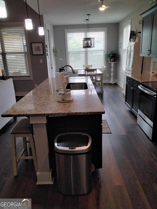 211 Barnyard Way, Perry, GA 31069 - kitchen featuring stainless steel range with electric cooktop, dark wood-style flooring, an island with sink, decorative light fixtures, and light stone countertops