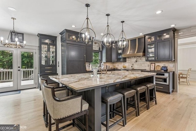 3835 Hickory Branch Trl, Suwanee, GA 30024 - kitchen with a chandelier, custom range hood, light wood-style floors, backsplash, and light stone countertops