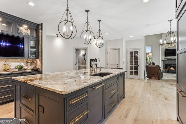 3835 Hickory Branch Trl, Suwanee, GA 30024 - kitchen featuring a chandelier, light wood finished floors, an island with sink, light stone counters, and recessed lighting