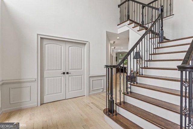 3835 Hickory Branch Trl, Suwanee, GA 30024 - stairway with wood finished floors, a decorative wall, wainscoting, and a towering ceiling