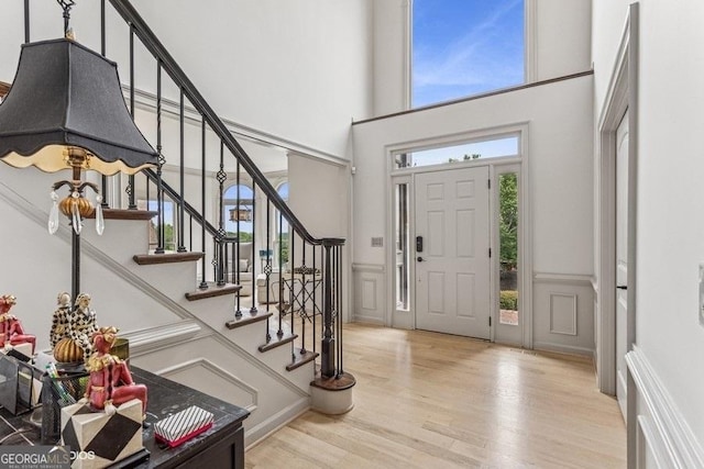 3835 Hickory Branch Trl, Suwanee, GA 30024 - foyer entrance featuring wood finished floors, a decorative wall, a towering ceiling, stairs, and a wainscoted wall