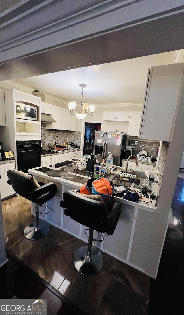 2481 Islands Hwy, Midway, GA 31320 - kitchen with black appliances, decorative backsplash, white cabinets, a breakfast bar, and a chandelier