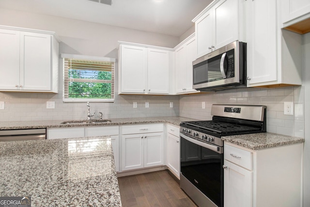 8041 Louis Dr, Locust Grove, GA 30248 - kitchen featuring stainless steel appliances, white cabinets, dark wood finished floors, tasteful backsplash, and light stone countertops