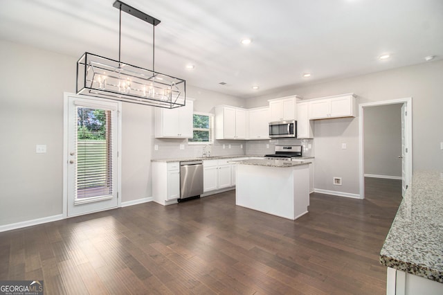 8041 Louis Dr, Locust Grove, GA 30248 - kitchen featuring stainless steel appliances, decorative backsplash, white cabinets, dark wood finished floors, and a kitchen island