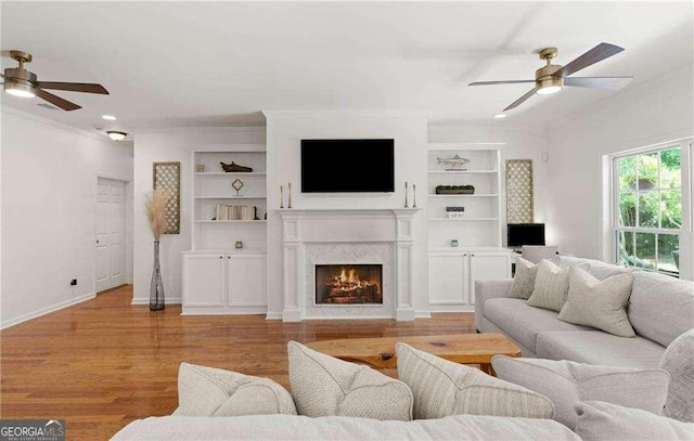 162 Drakes Lndg, Brunswick, GA 31523 - living area featuring ceiling fan, built in features, wood finished floors, a warm lit fireplace, and ornamental molding