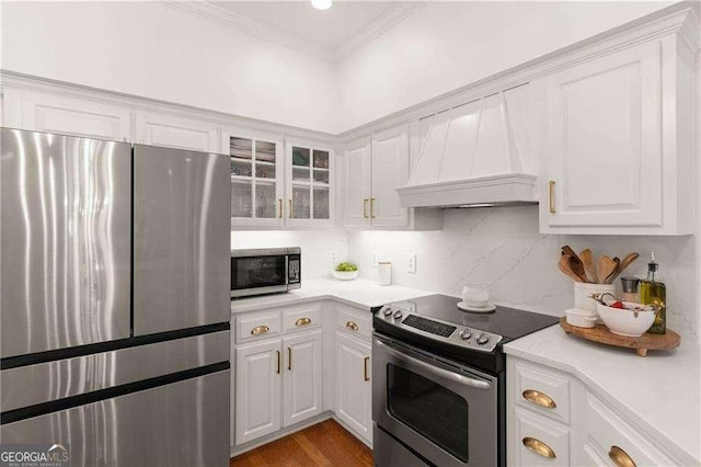 162 Drakes Lndg, Brunswick, GA 31523 - kitchen with appliances with stainless steel finishes, custom range hood, light countertops, white cabinetry, and ornamental molding