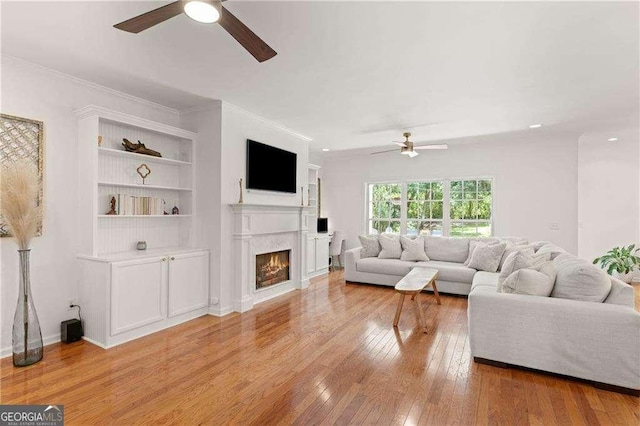 162 Drakes Lndg, Brunswick, GA 31523 - living area featuring a ceiling fan, light wood-style floors, a lit fireplace, crown molding, and built in shelves