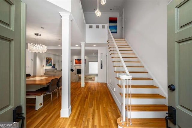 4569 Fountain Dr, Marietta, GA 30067 - stairs with decorative columns, ornamental molding, wood finished floors, and a fireplace