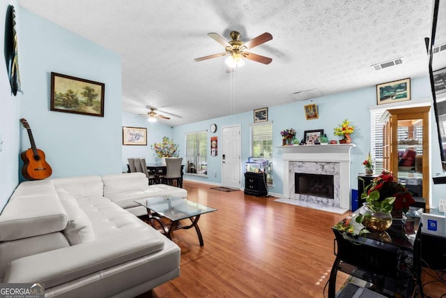 580 Lilburn School Rd, Lilburn, GA 30047 - living area with ceiling fan, wood finished floors, a textured ceiling, and a high end fireplace