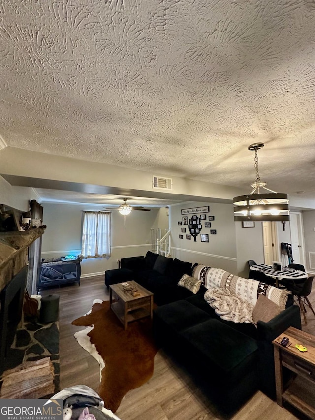 317 Running Deer Rd, Cleveland, GA 30528 - living area with a textured ceiling, wood finished floors, a stone fireplace, and ceiling fan