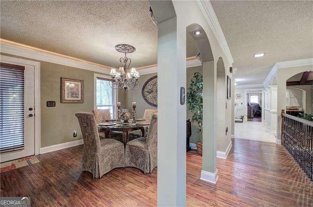 186 Wolverine Dr, Waleska, GA 30183 - dining room with a textured ceiling, crown molding, a chandelier, wood finished floors, and arched walkways