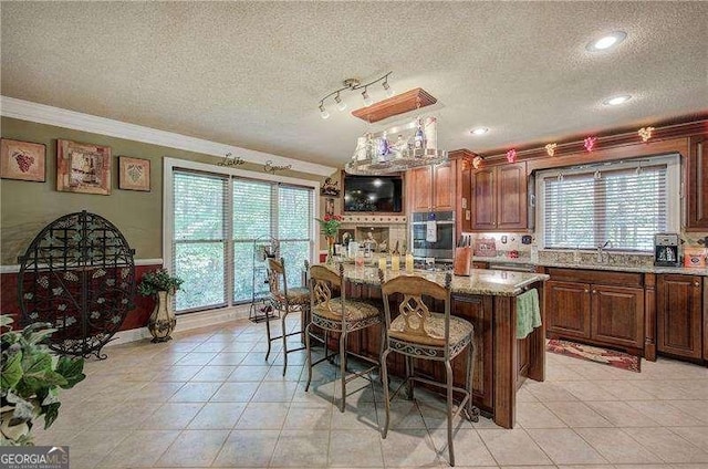 186 Wolverine Dr, Waleska, GA 30183 - kitchen featuring oven, a textured ceiling, crown molding, a breakfast bar, and light stone counters