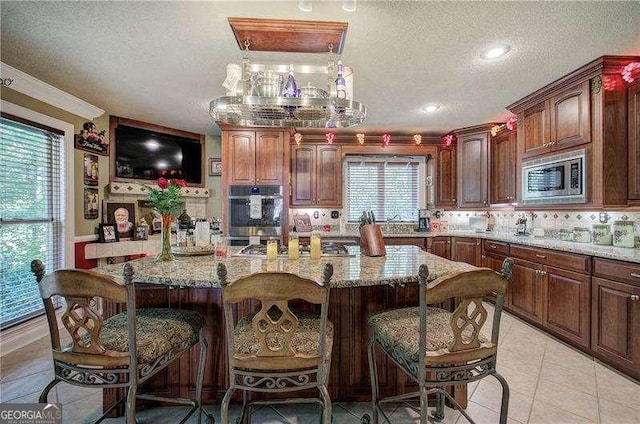 186 Wolverine Dr, Waleska, GA 30183 - kitchen with appliances with stainless steel finishes, light stone counters, a breakfast bar, a kitchen island, and a textured ceiling