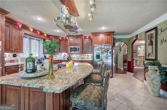 186 Wolverine Dr, Waleska, GA 30183 - kitchen featuring appliances with stainless steel finishes, arched walkways, a textured ceiling, backsplash, and light stone counters