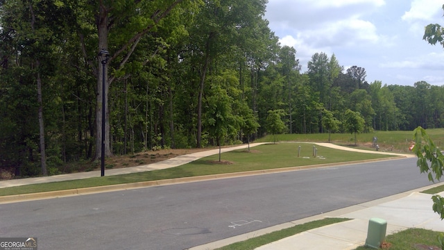 11893 Aukerman Way, Hampton, GA 30228 - view of asphalt road featuring sidewalks, street lights, a forest view, and curbs