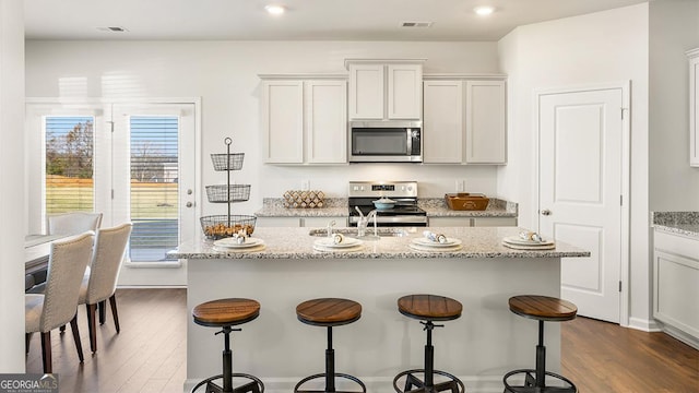11893 Aukerman Way, Hampton, GA 30228 - kitchen with appliances with stainless steel finishes, dark wood-style floors, a kitchen breakfast bar, a center island with sink, and recessed lighting