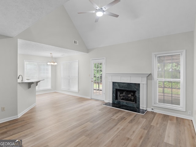 404 Northwind Pl, Stockbridge, GA 30281 - unfurnished living room featuring a chandelier, light wood-style flooring, a fireplace, a ceiling fan, and high vaulted ceiling