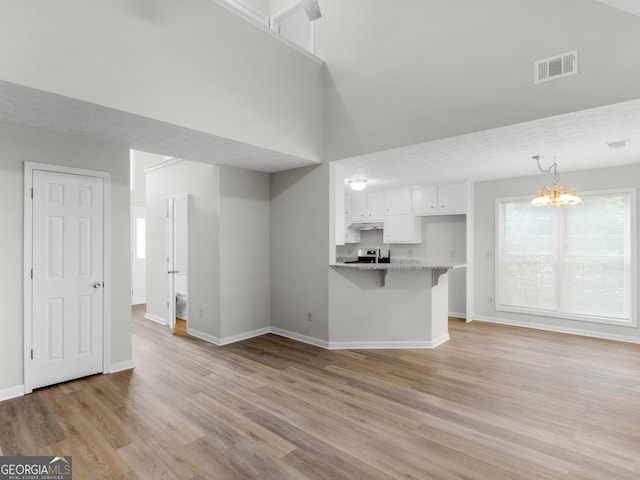 404 Northwind Pl, Stockbridge, GA 30281 - unfurnished living room featuring light wood-style floors, a chandelier, and a towering ceiling