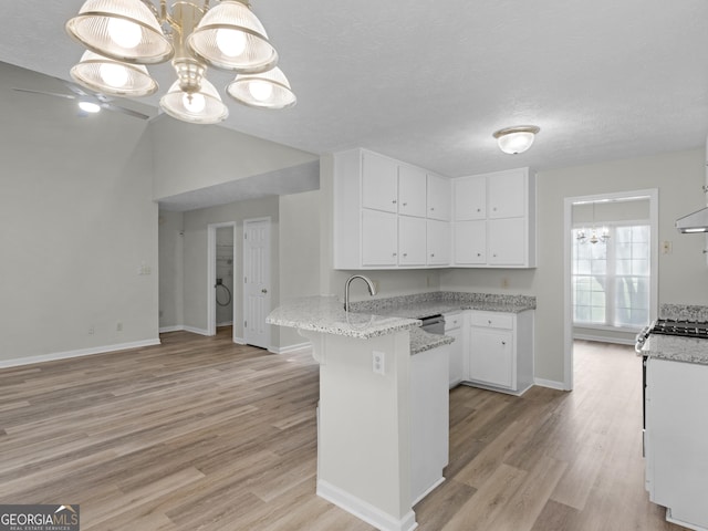 404 Northwind Pl, Stockbridge, GA 30281 - kitchen with a peninsula, a chandelier, light wood-style floors, white cabinetry, and light stone counters