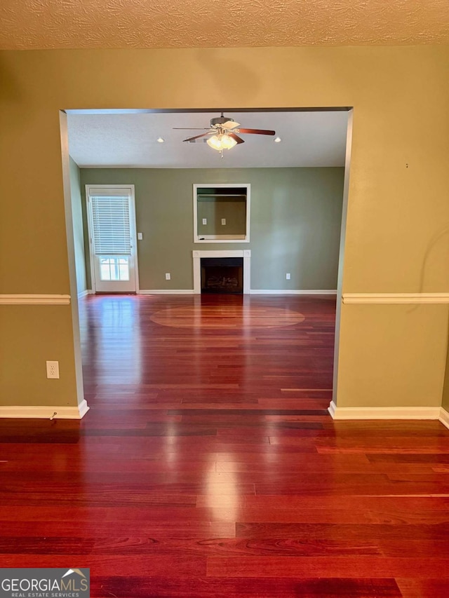 1013 Navaho Trl, Monroe, GA 30655 - unfurnished living room featuring ceiling fan, wood finished floors, a fireplace, and a textured ceiling