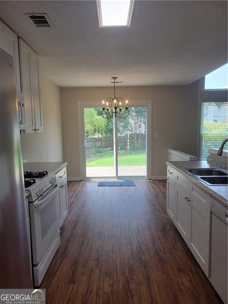 13565 Weycroft Cir, Alpharetta, GA 30004 - kitchen featuring white appliances, white cabinets, dark wood-style flooring, and a chandelier