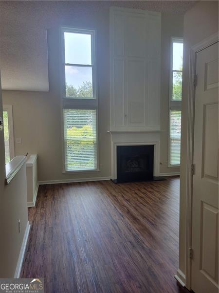 13565 Weycroft Cir, Alpharetta, GA 30004 - unfurnished living room featuring dark wood-style floors, a fireplace, and healthy amount of natural light