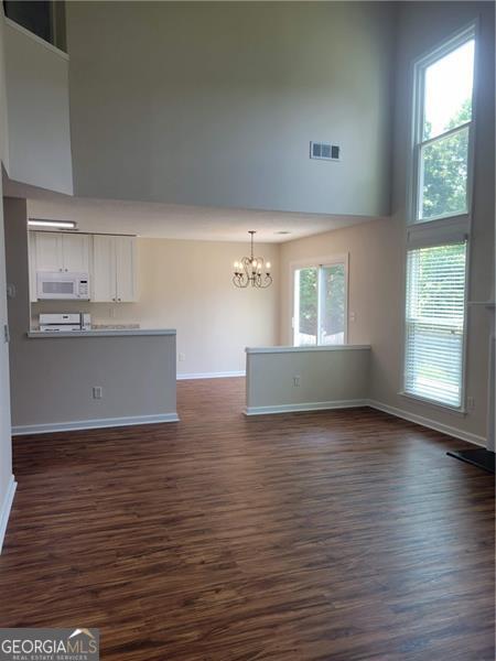 13565 Weycroft Cir, Alpharetta, GA 30004 - unfurnished living room featuring a chandelier, a towering ceiling, and dark wood-style floors