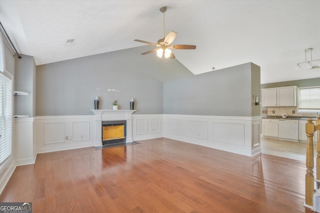 375 Shadetree Ln, Lawrenceville, GA 30044 - unfurnished living room with a ceiling fan, lofted ceiling, a fireplace with flush hearth, light wood-type flooring, and wainscoting