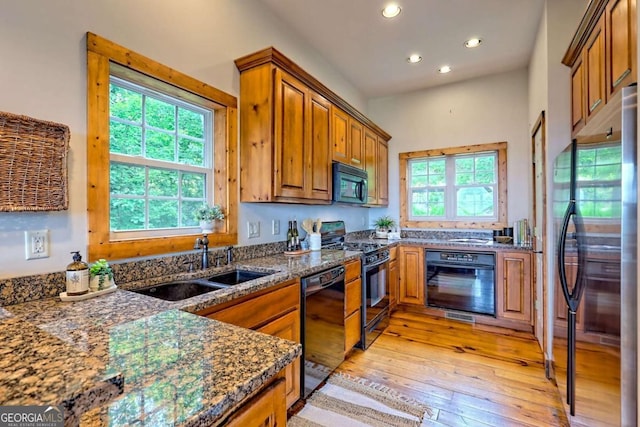 990 Hickory Nut Mountain Rd, Tallulah Falls, GA 30573 - kitchen with black appliances, brown cabinetry, healthy amount of natural light, recessed lighting, and dark stone countertops