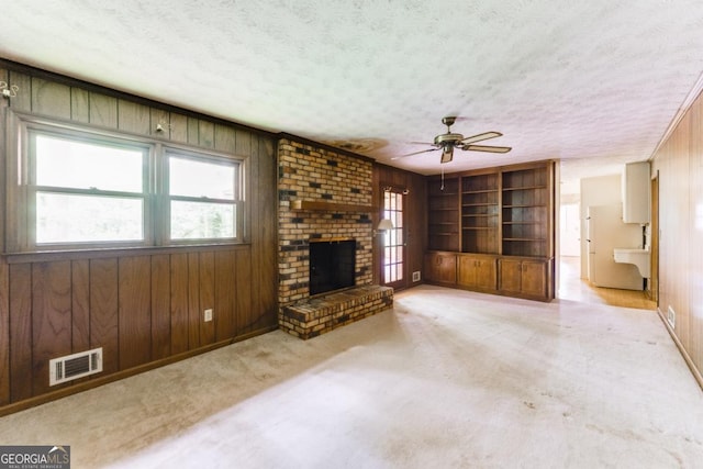 4714 Darlene Way, Tucker, GA 30084 - unfurnished living room with a textured ceiling, ceiling fan, plenty of natural light, built in shelves, and wooden walls