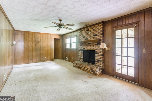 4714 Darlene Way, Tucker, GA 30084 - unfurnished living room featuring a textured ceiling, wooden walls, ceiling fan, a fireplace, and carpet